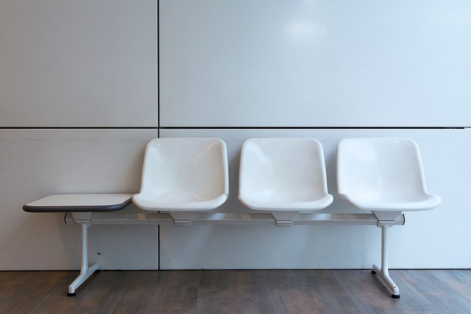 A clean, minimal clinic waiting bench against a white wall